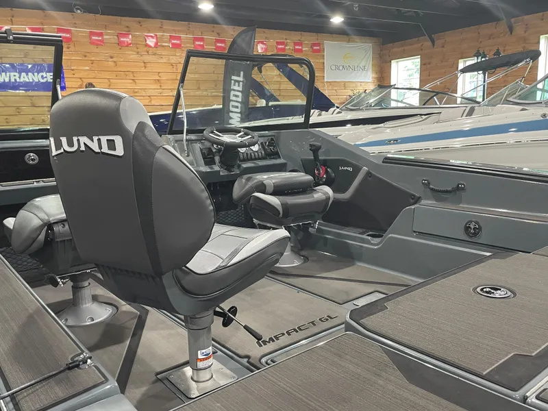 Slide: The Image of 2025 Lund 185 Impact GL boat interior with steering console and seating in showroom. - 8