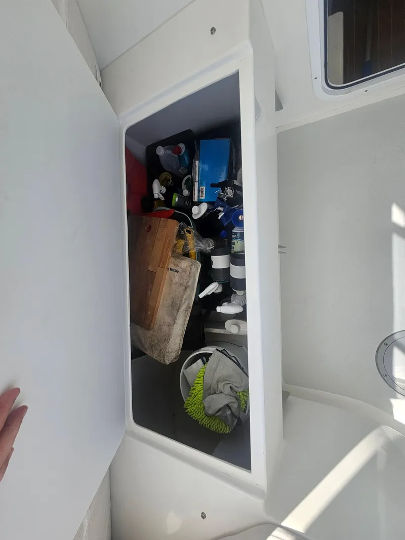Slide: The Image of Storage compartment on a 2019 Eastern 248 Explorer boat, filled with various items. - 12