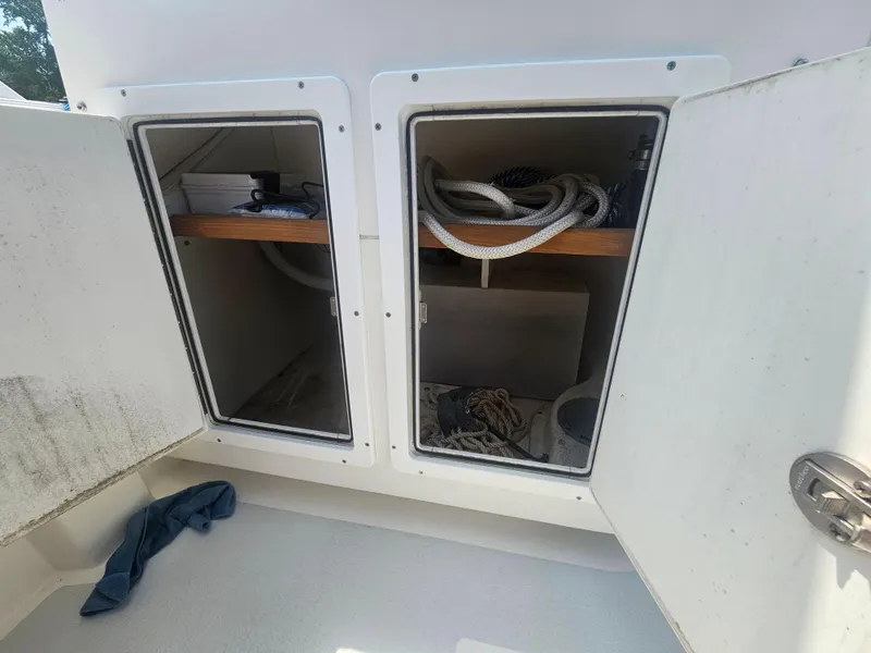Slide: The Image of Open storage compartments on a 2019 Eastern 248 Explorer boat, containing ropes and equipment. - 14
