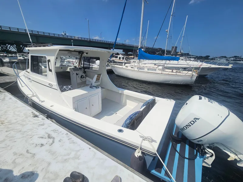 Slide: The Image of 2019 Eastern 248 Explorer boat docked, featuring a Honda outboard motor, under a clear blue sky. - 17