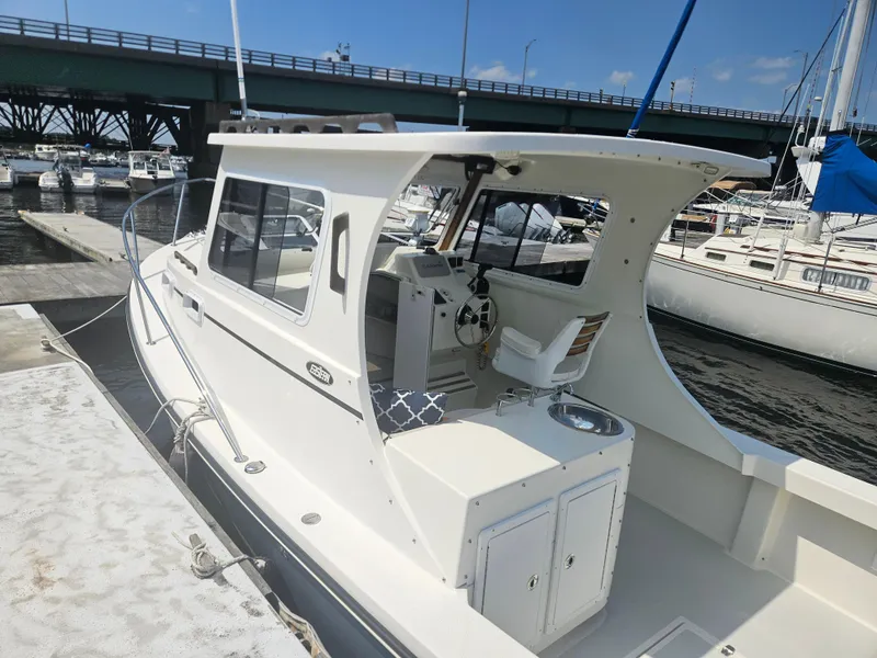 Slide: The Image of 2019 Eastern 248 Explorer boat docked at marina, featuring a spacious cockpit and helm. - 18