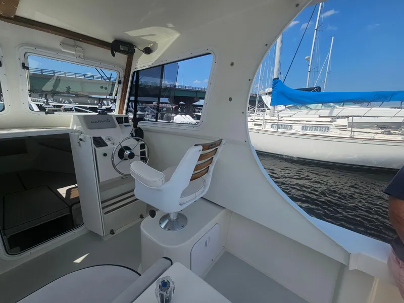 Slide: The Image of Interior of a 2019 Eastern 248 Explorer boat with steering wheel and marina view. - 7