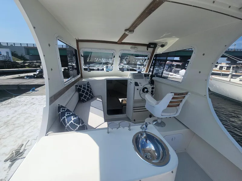 Slide: The Image of 2019 Eastern 248 Explorer boat interior with helm, seating, and sink, docked at marina. - 8