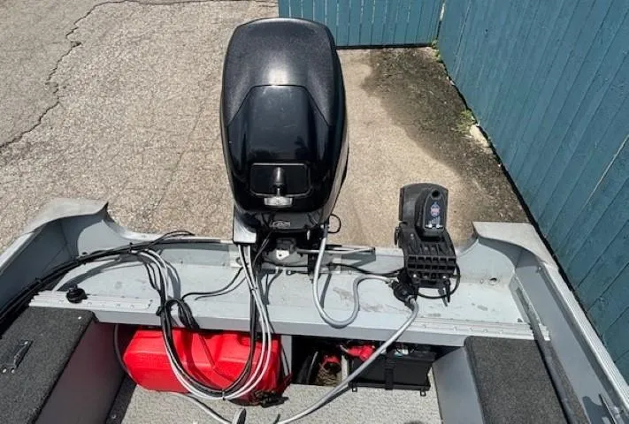 Slide: The Image of 2013 Lund 1400 Fury SS boat with motor and fuel tank, parked near a blue fence. - 21