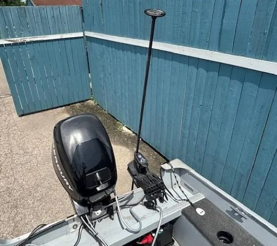 Slide: The Image of 2013 Lund 1400 Fury SS boat with motor and equipment, parked by a blue fence. - 23