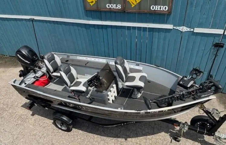 Slide: The Image of 2013 Lund 1400 Fury SS fishing boat with motor, trailer, and seating, parked outdoors. - 4