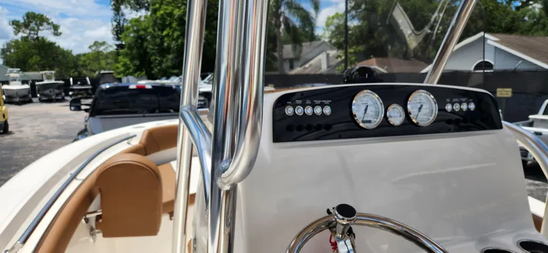 Slide: The Image of 2026 Pioneer 202 Sportfish boat dashboard with gauges and steering wheel, parked outdoors. - 10