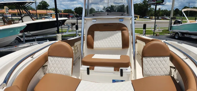 Slide: The Image of 2026 Pioneer 202 Sportfish boat interior with tan and white seating, parked outdoors. - 14
