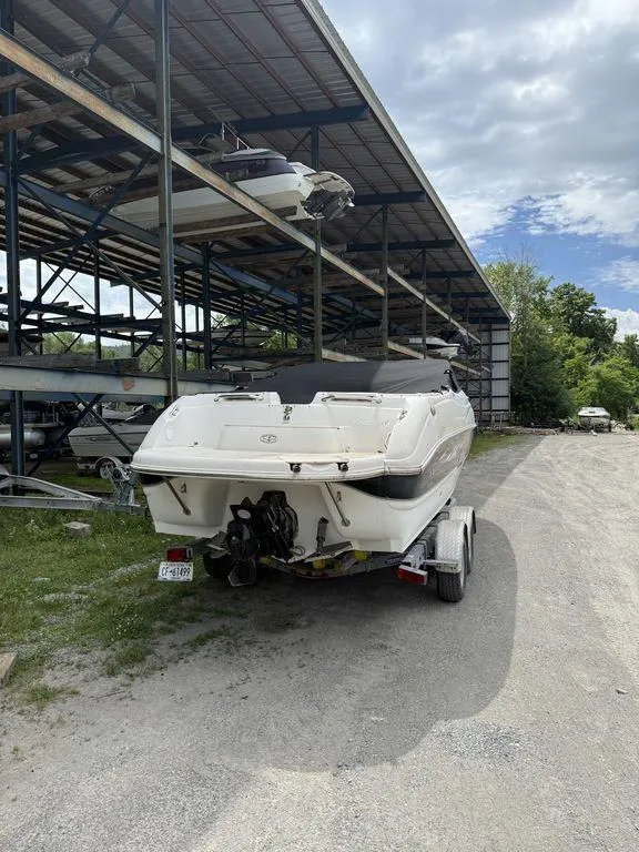 Slide: The Image of 2007 Stingray 220DR boat on trailer, parked under metal shelter, cloudy sky background. - 6