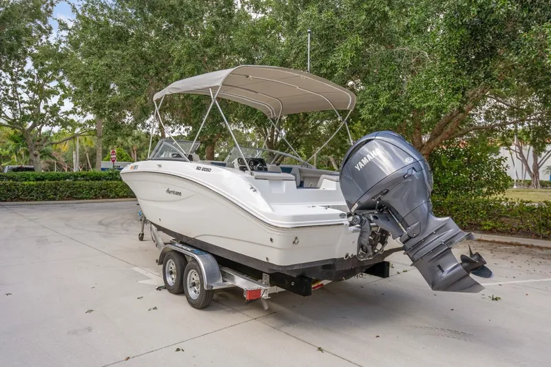 Slide: The Image of 2025 Hurricane SunDeck 2050 OB boat on trailer with Yamaha outboard motor, parked outdoors. - 1