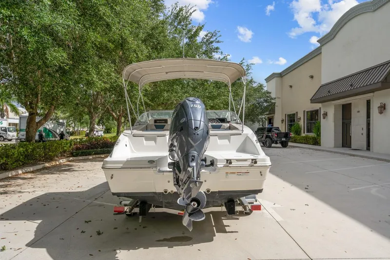Slide: The Image of 2025 Hurricane SunDeck 2050 OB boat with outboard motor in a sunny parking lot. - 6