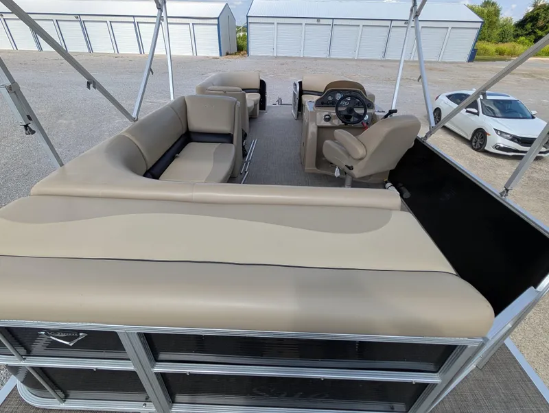 Slide: The Image of 2016 Manitou 23 Aurora pontoon boat interior with beige seating and steering console. - 16