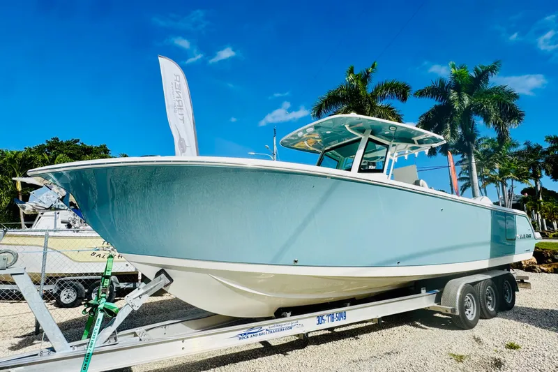 The Image of 2026 Sailfish 312 CC boat on trailer, under clear blue sky with palm trees. - 2