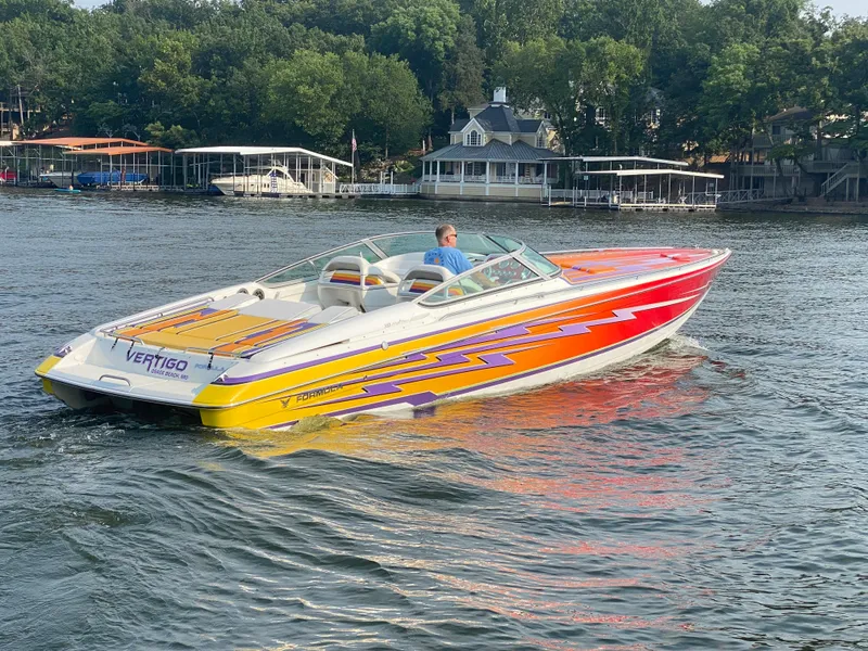 Slide: The Image of 2006 Formula 353 FASTech speedboat with vibrant graphics cruising on a lake. - 5
