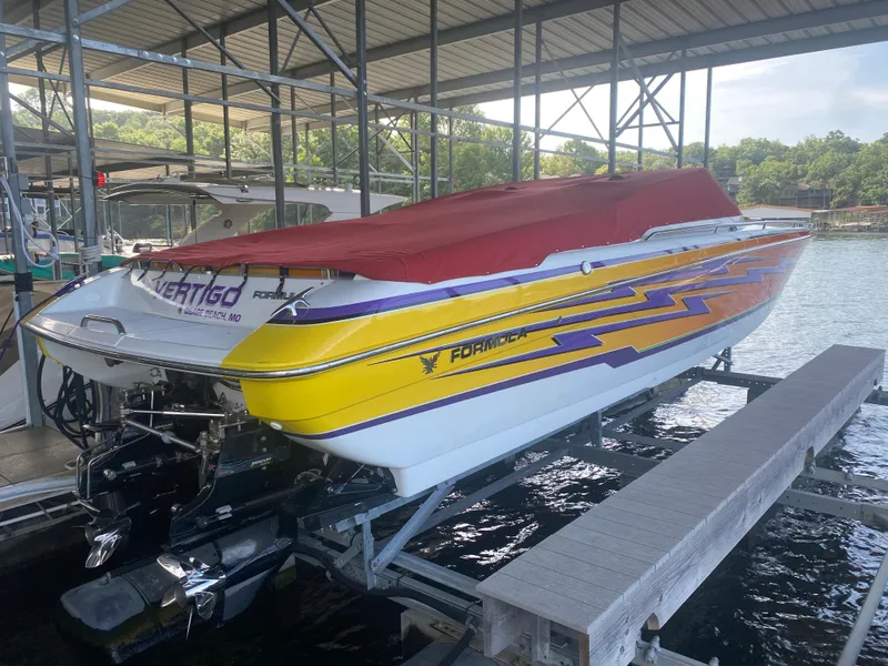 Slide: The Image of 2006 Formula 353 FASTech speedboat with vibrant graphics, docked under a covered marina. - 50