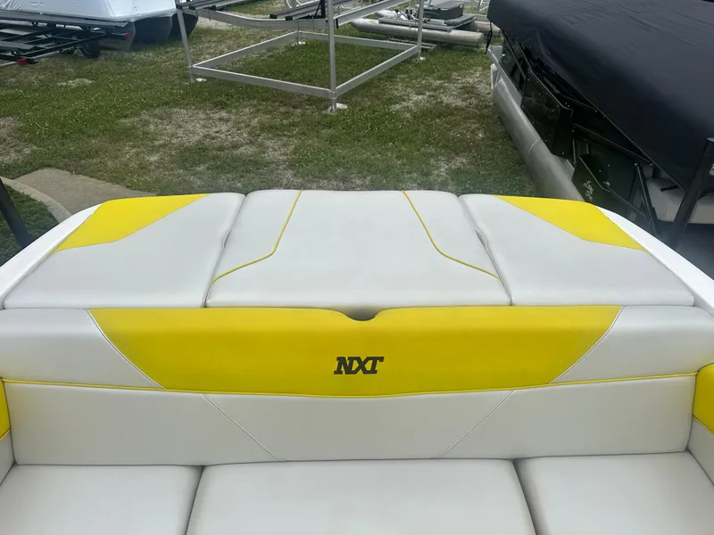 Slide: The Image of 2018 MasterCraft NXT22 boat with yellow and white seating, parked on grass. - 14