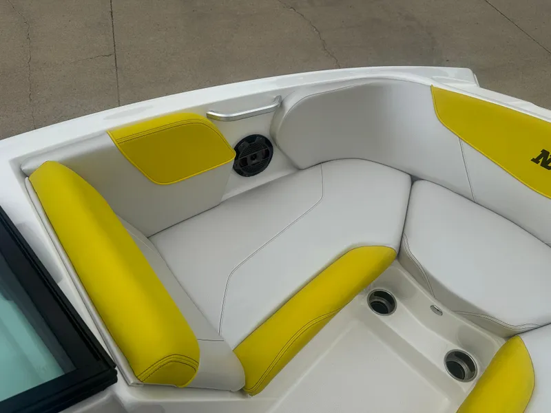 Slide: The Image of 2018 MasterCraft NXT22 boat interior with yellow and white seating, featuring cup holders and speaker. - 20