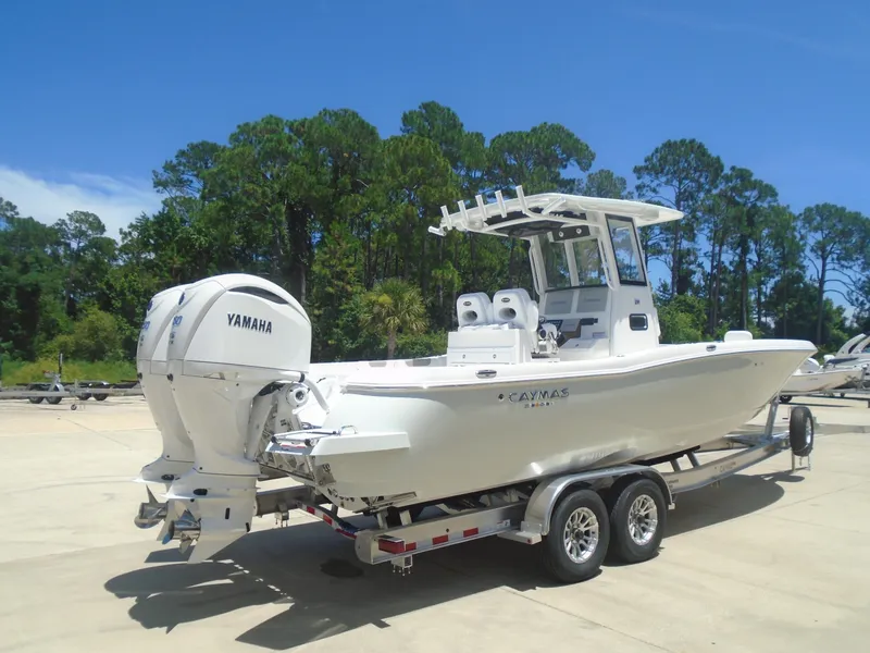 Slide: The Image of 2025 Caymas 291 boat with Yamaha engines on a trailer, surrounded by trees. - 2