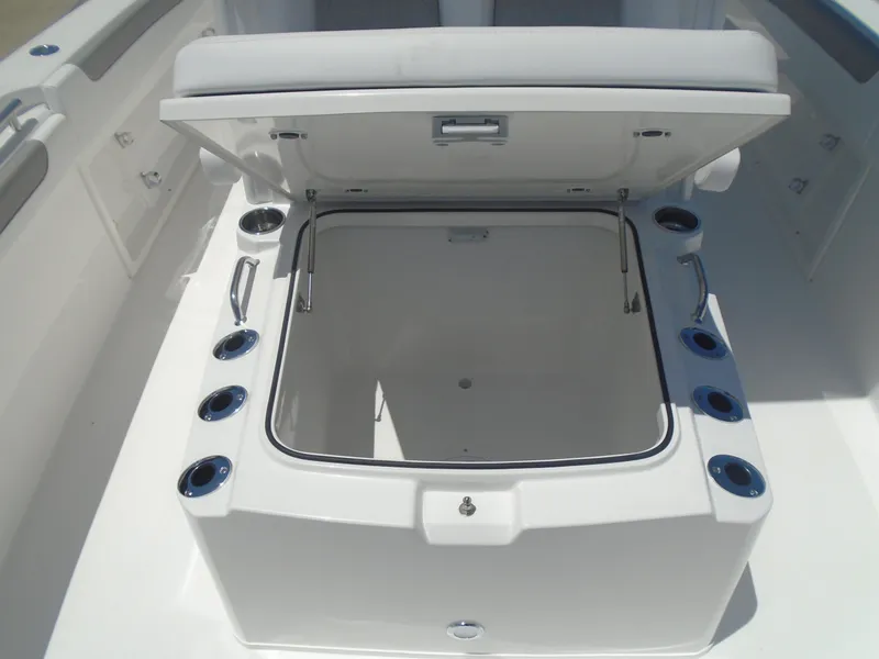 Slide: The Image of 2025 Caymas 291 boat storage compartment with open lid, showcasing spacious interior and cup holders. - 29