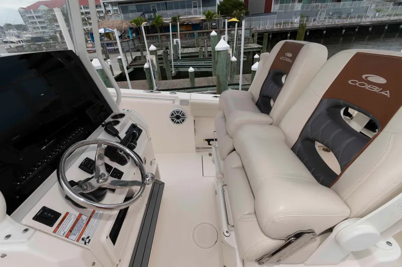 Slide: The Image of 2023 Cobia 280 Center Console boat interior with steering wheel and cushioned seats. - 11
