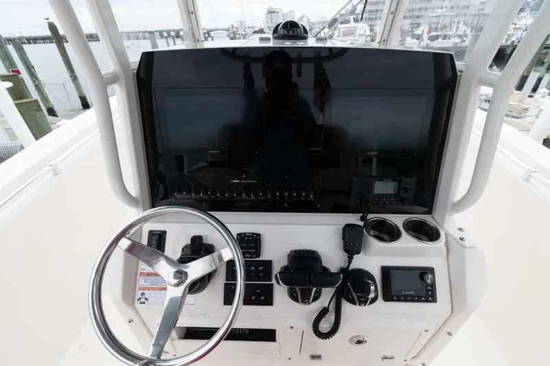 Slide: The Image of 2023 Cobia 280 Center Console boat dashboard with steering wheel and navigation controls. - 12