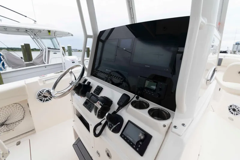 Slide: The Image of 2023 Cobia 280 Center Console boat dashboard with steering wheel and electronic controls. - 13