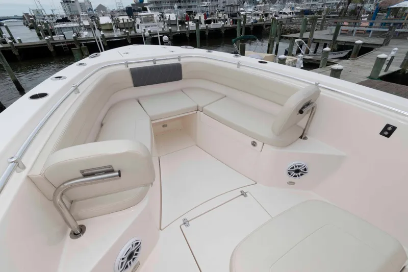 Slide: The Image of 2023 Cobia 280 Center Console boat interior with spacious seating at a marina. - 15