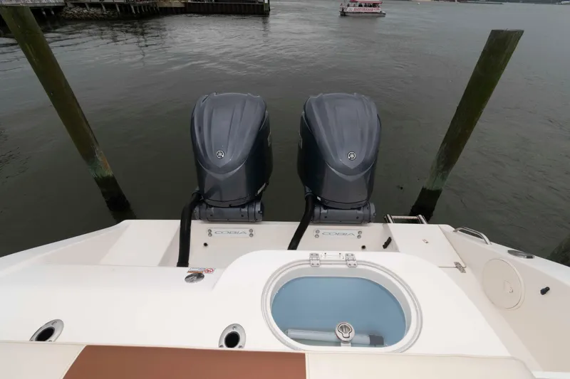 Slide: The Image of 2023 Cobia 280 Center Console boat with dual outboard engines on water. - 19