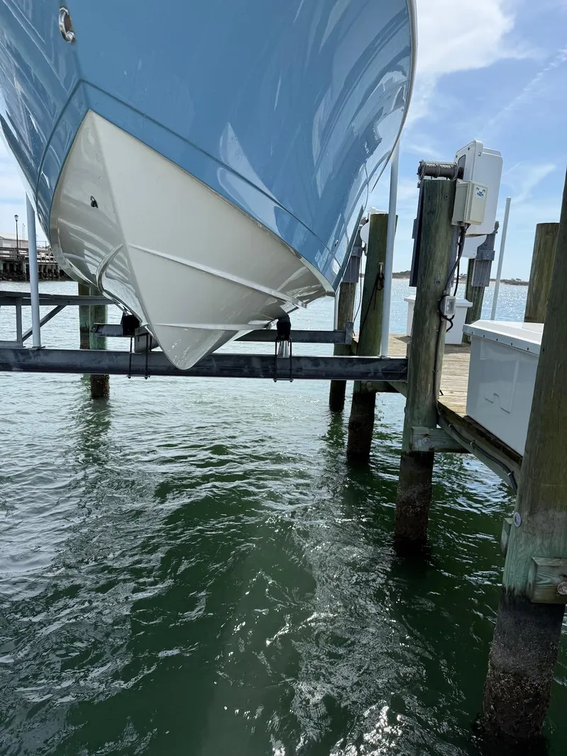 Slide: The Image of 2023 Cobia 280 Center Console boat on lift above water. - 2