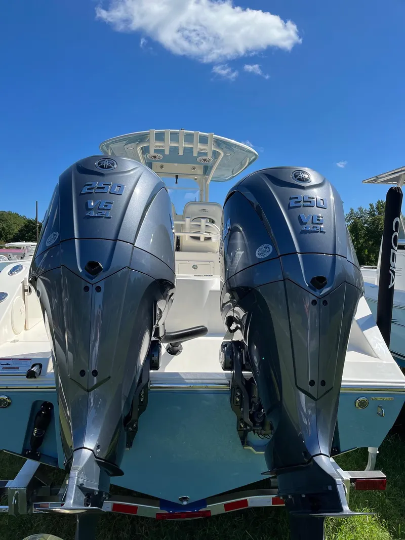 Slide: The Image of 2023 Cobia 280 Center Console with dual 250 V6 outboard engines, under clear blue sky. - 24