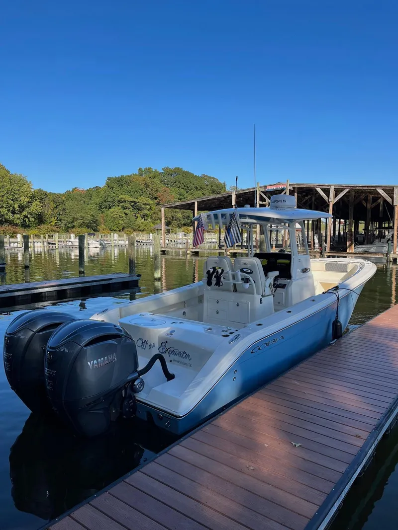 Slide: The Image of 2023 Cobia 280 Center Console boat docked with twin Yamaha engines. - 3