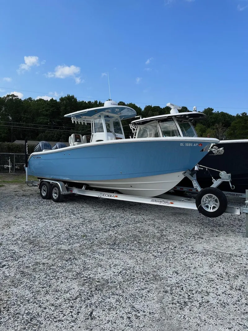 Slide: The Image of 2023 Cobia 280 Center Console boat on trailer, parked outdoors under blue sky. - 4