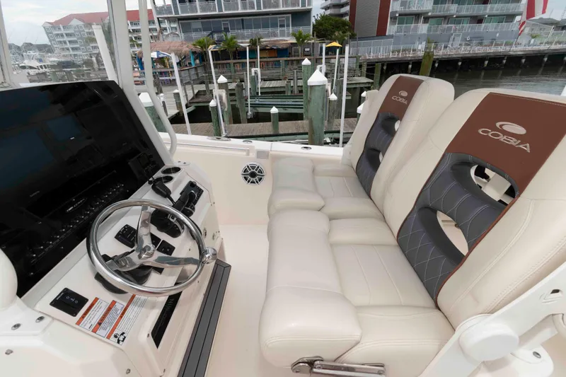 Slide: The Image of 2023 Cobia 280 Center Console boat interior with steering wheel and cushioned seats. - 8