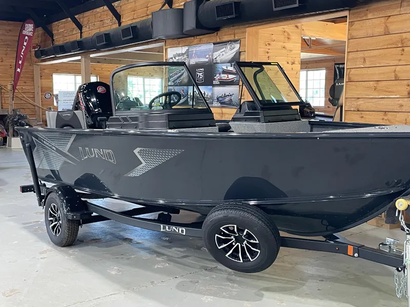 Slide: The Image of 2026 Lund 1775 Adventure Sport boat in showroom, sleek black design, on trailer. - 3