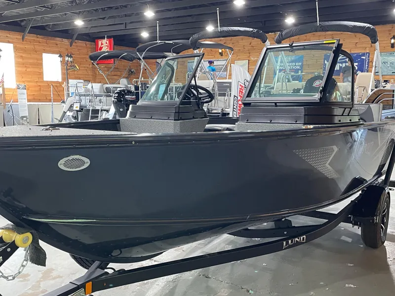 Slide: The Image of 2026 Lund 1775 Adventure Sport boat in showroom, sleek black design, dual windshields. - 4