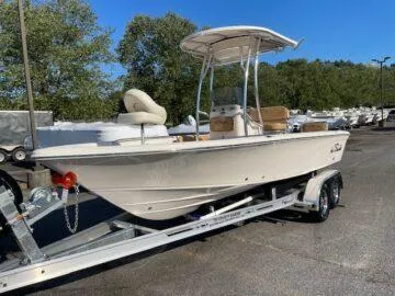Slide: The Image of 2024 Sea Chaser LX boat on trailer, parked outdoors, surrounded by trees and other boats. - 2