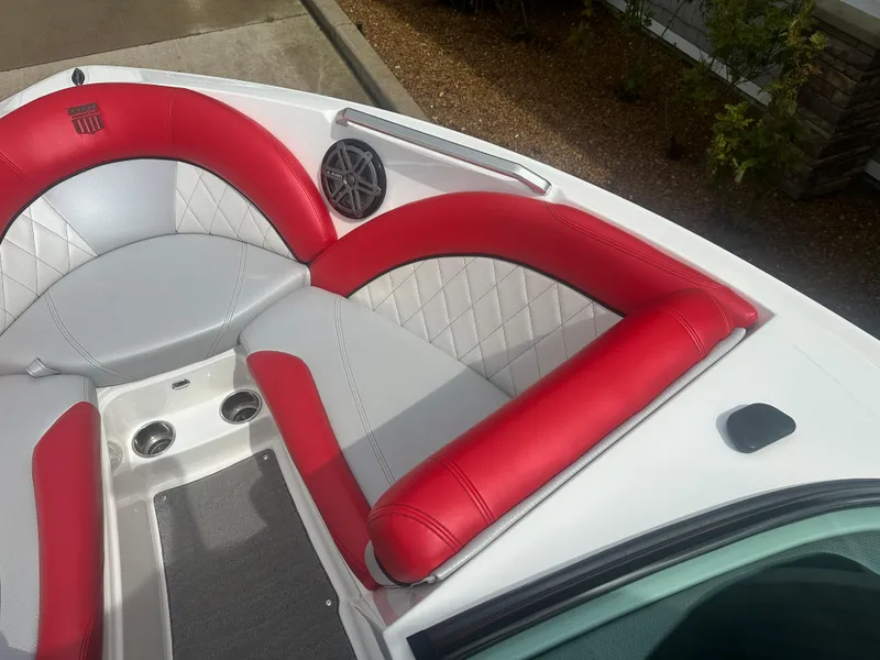 Slide: The Image of 2015 MasterCraft X10 boat interior with red and gray seating, cup holders, and speaker. - 12