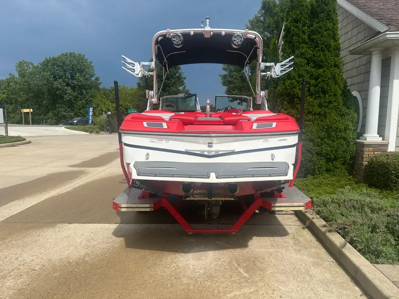 Slide: The Image of 2015 MasterCraft X10 boat on trailer, parked in driveway, surrounded by greenery. - 3