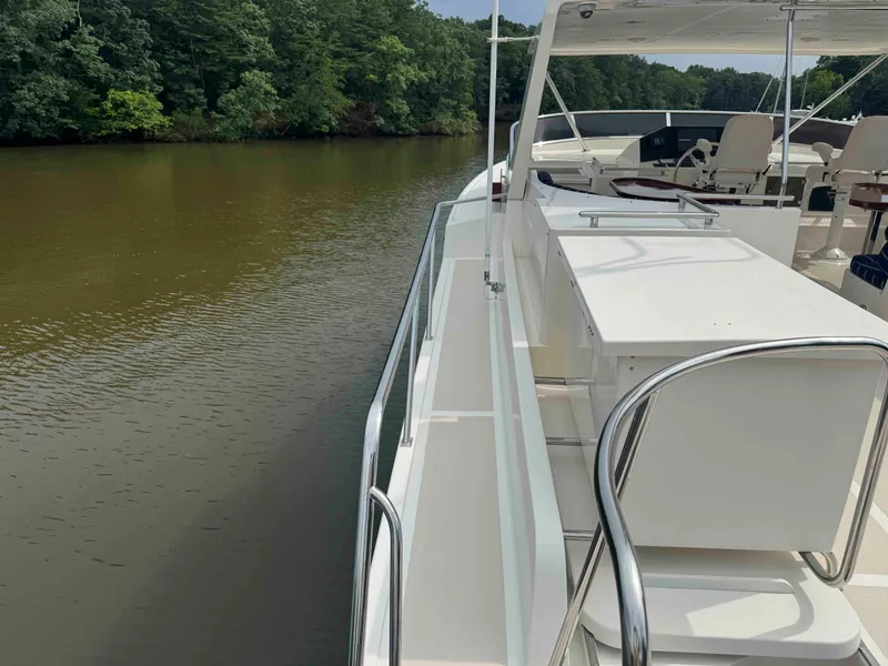 Slide: The Image of Side view of a 2002 Marlow 70E yacht on a calm river, surrounded by lush greenery. - 13