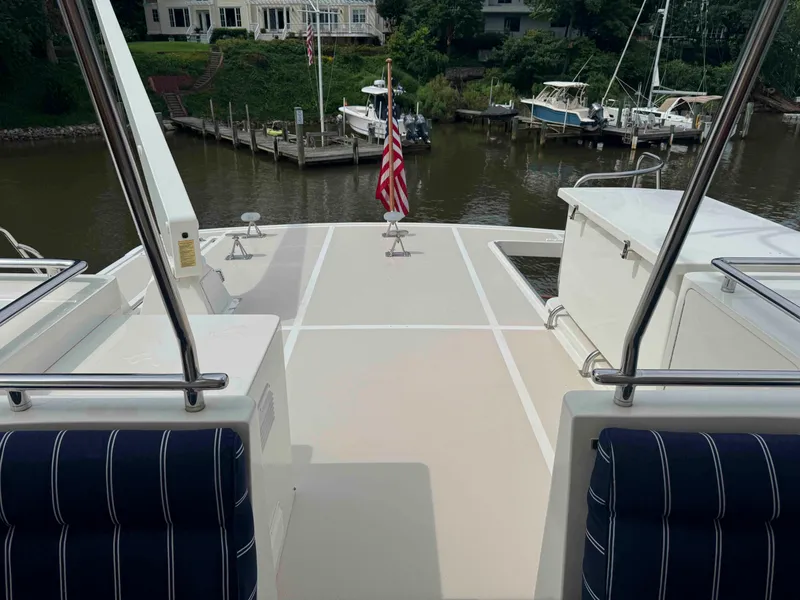 Slide: The Image of Deck view of 2002 Marlow 70E yacht with American flag, docked near waterfront homes. - 20