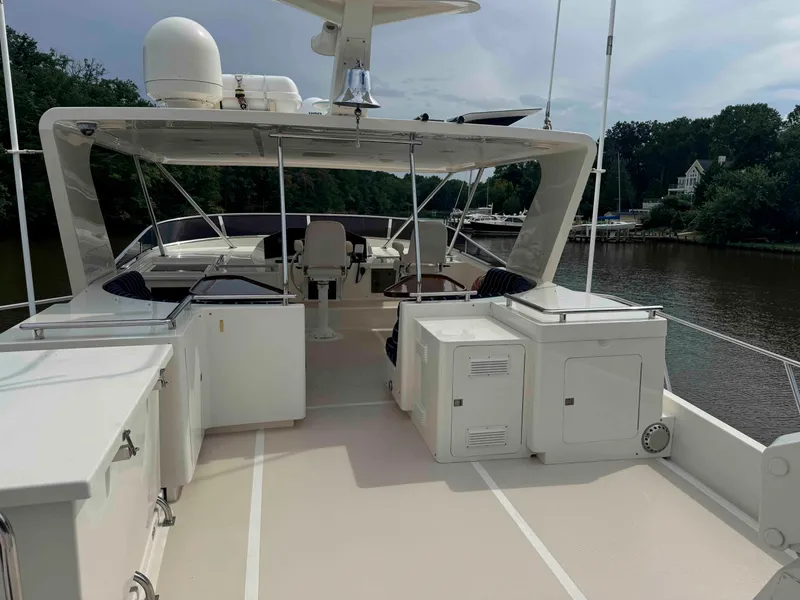 Slide: The Image of Luxury Marlow 70E yacht deck, 2002 model, with seating and storage, docked by a river. - 23