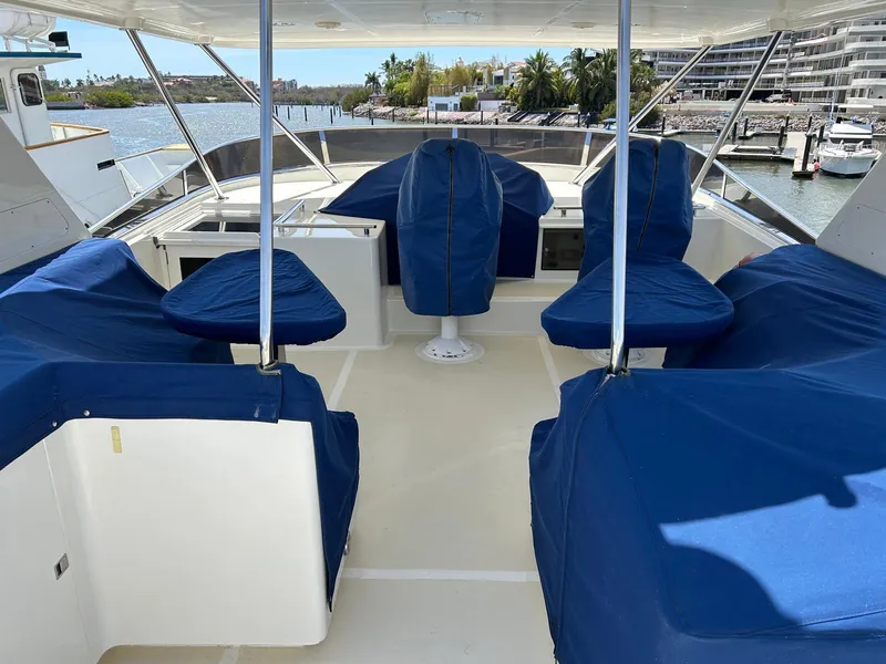 Slide: The Image of Flybridge of 2002 Marlow 70E yacht with blue-covered seating, overlooking marina. - 28