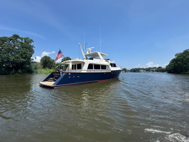 Slide: The Image of Luxury Marlow 70E yacht from 2002 on a serene river under clear blue skies. - 3