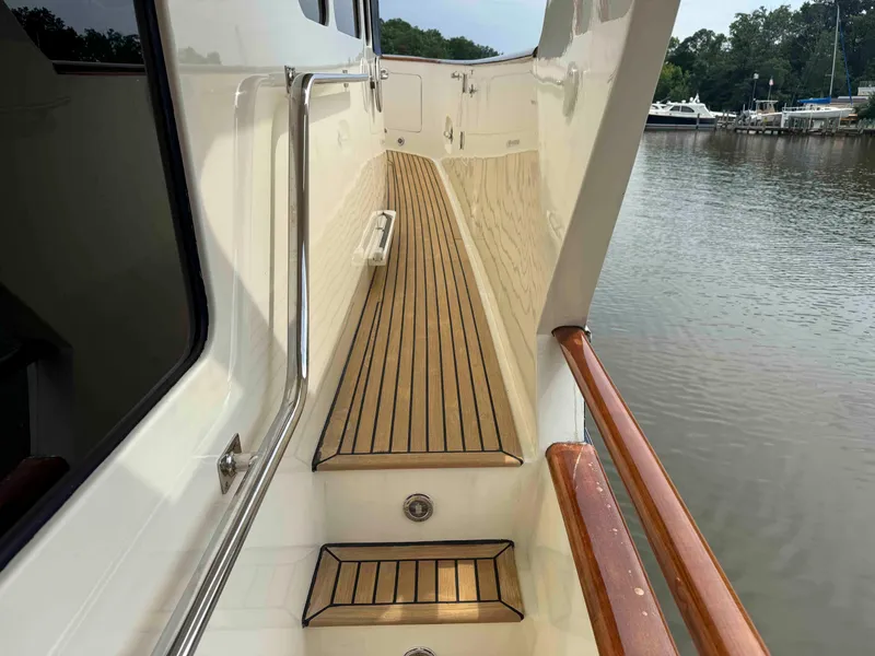 Slide: The Image of Side deck of 2002 Marlow 70E yacht with wooden flooring and railing, near water. - 34