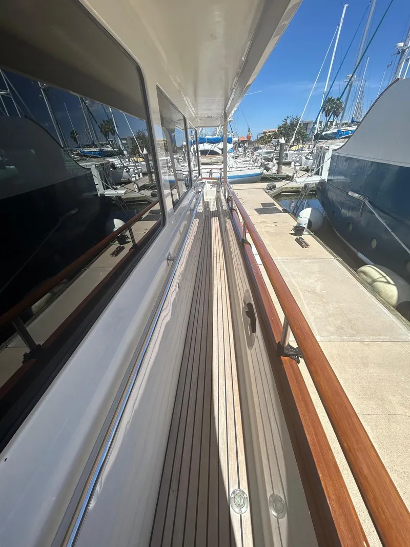 Slide: The Image of Side deck view of 2002 Marlow 70E yacht in marina, showcasing teak flooring and railing. - 37