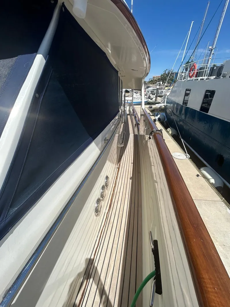 Slide: The Image of Side deck view of a 2002 Marlow 70E yacht, featuring teak wood and polished metal details. - 38