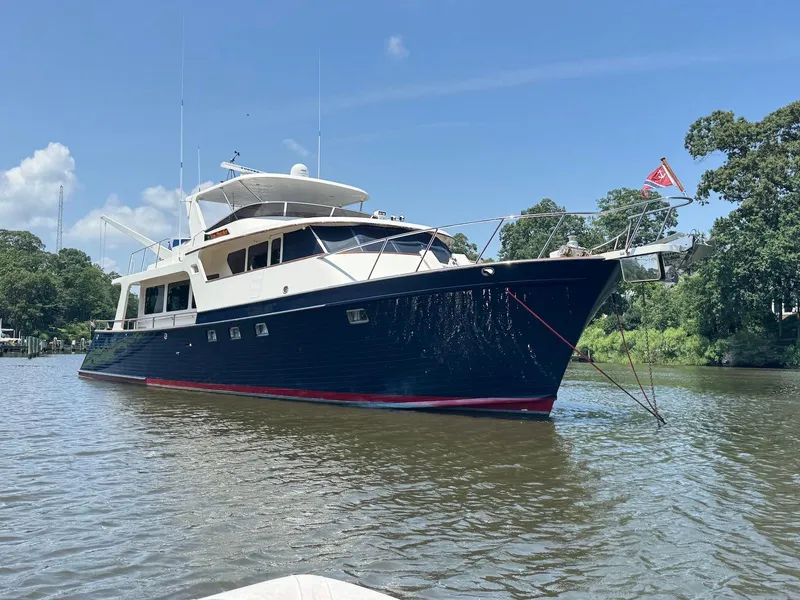 Slide: The Image of Luxury 2002 Marlow 70E yacht anchored on a serene river under a clear blue sky. - 4