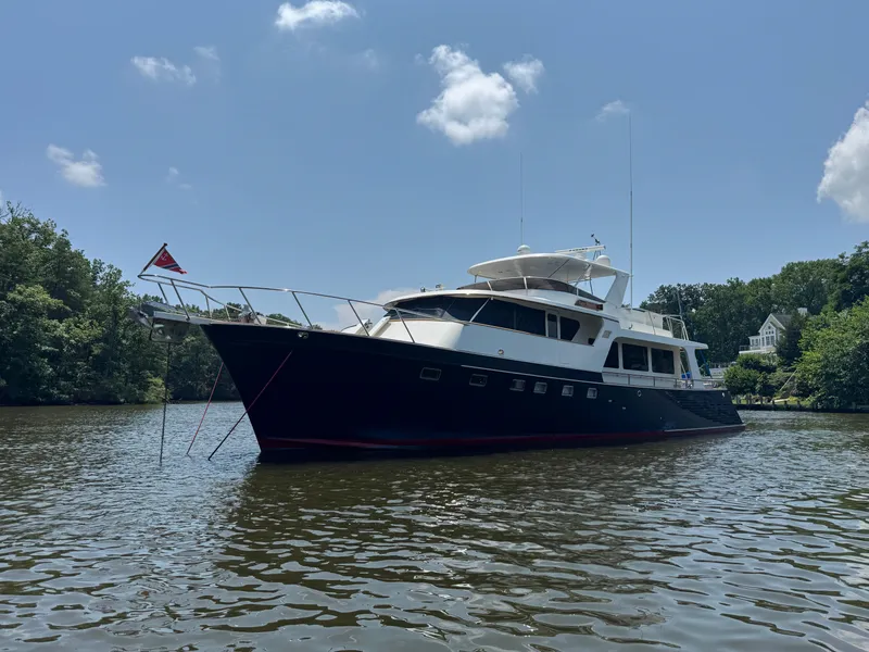 Slide: The Image of Luxury Marlow 70E yacht from 2002 on a serene river under a clear sky. - 6