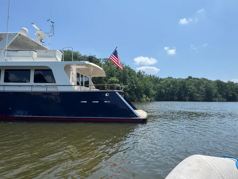 Slide: The Image of Marlow 70E yacht from 2002 on a serene lake with American flag. - 8