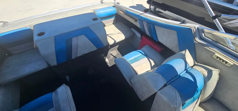 Slide: The Image of 1989 Galaxie 1900 Starion boat interior with blue and gray seating, cup holders, and open layout. - 11
